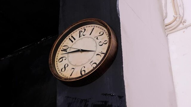 A classic vintage and old looking round clock with moving seconds hand in the living room house on black and white wall