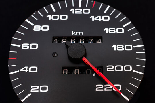 Car speedometer. Auto car speedometer shows 220 km h or miles.Closeup shot,dark black background.Automobile dangerous speed concept