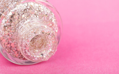 glitter transparent nail polish on a pink background close up