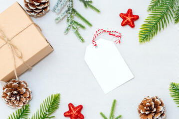 Christmas blank greeting card in frame of fir branches, decorations, gift box and cones over white background.mockup. flat lay. top view.