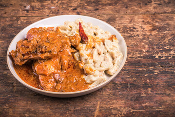 Chicken stew with paprika and cream in a plate with homemade gnocchi, copy space for recipe, chicken paprikash, hungarian cuisine