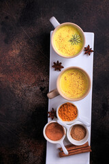 Easy Healthy Golden Milk, Turmeric Latte over dark background. Spices for ayurvedic treatment. Alternative medicine concept.