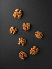 Walnut kernels on a black matte background.