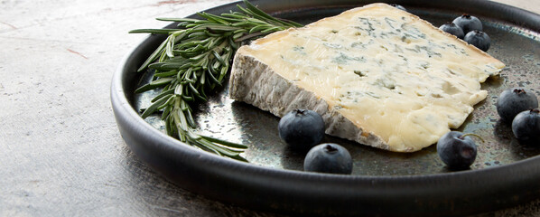 ceramic dish with gorgonzola cheese, rosemary and blueberries on the table - obrazy, fototapety, plakaty