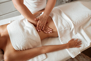 Fototapeta na wymiar Young woman receiving abdominal massage in spa salon