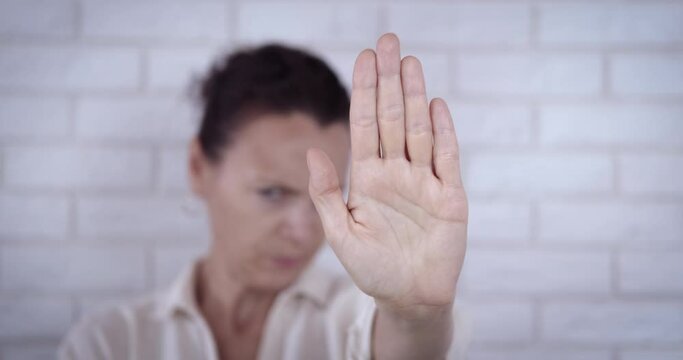 Woman stretch out her palm. A stressed woman show a stop sign with her palm because of social aggression.