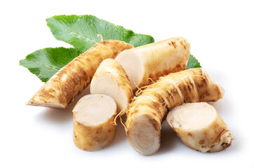 Horseradish roots and green leaves close up on the white background.