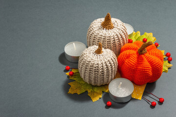 Autumn composition with crocheted pumpkins, candles, leaves, and traditional decor