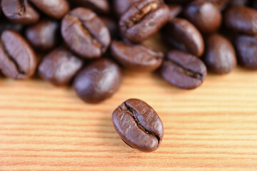 Closeup an Arabica Roasted Coffee Bean with Blurry Coffee Beans Pile in the Backdrop