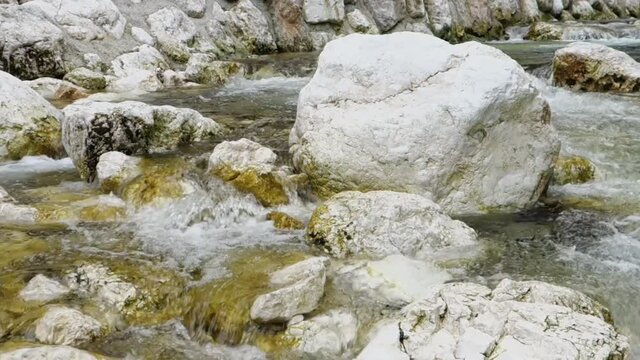 Stones and crystal clear water in Sava Bohinjka river in Slovenia with panning motion