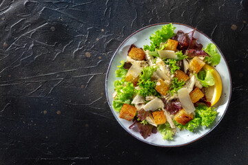 Chicken Caesar salad, shot from above on a dark rustic wooden background. Healthy and delicious meal, with a place for text