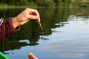 fishing lure held in hand, spinner with a triple hook, a fishing lure is a type of artificial...
