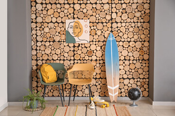 Interior of modern stylish room with surfboard and chairs near wooden wall