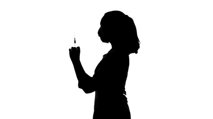 Photo of woman's silhouette in mask with syringe in profile