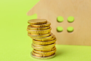 Coins with model of house on color background