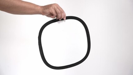A man's hand holds a gray card in front of the video camera to check the white balance