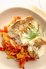 Plate with tasty baked cod fillet, vegetables and sauce on light background, closeup