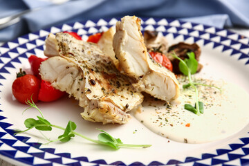Plate with tasty baked cod fillet, vegetables and sauce, closeup