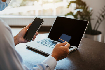 Male businessmen use credit cards to conduct financial transactions through phones  and laptop in the morning.