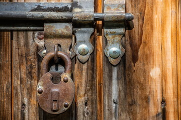 Close up view of the old rusty padlock on a aged gray wooden door