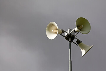three white megaphones against a dark dramatic sky