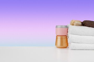 Pile of towels, bottles with shampoo on white table