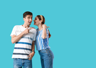 Young gossip couple pointing at something on blue background
