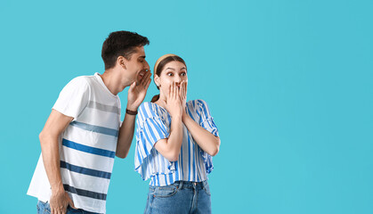Young man sharing gossip with his girlfriend on blue background