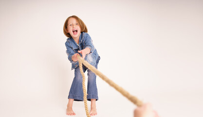 Portrait kleines Mädchen zieht fröhlich an einem Seil, weißer Hintergrund Vs1