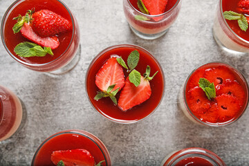 Glasses with tasty strawberry panna cotta and mint on light background