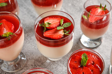 Glasses with tasty strawberry panna cotta and mint on light background, closeup