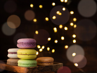 stack of macaroons on the table, fairy lights and bokeh background