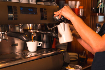 A waitress at a coffee machine putting a decaf into a white cup