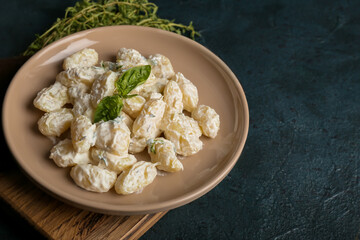 Plate of delicious gnocchi with creamy sauce on black background