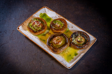 Mushrooms with olive oil and garlic on a black background, on a white plate