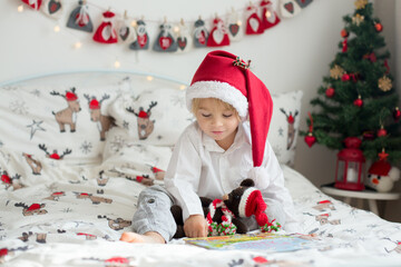 Beautiful toddler child, reading book in bed on Christmas