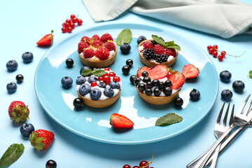 Composition with tasty berry tartlets on color background