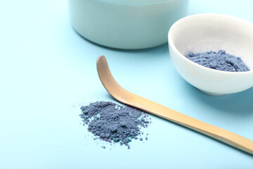 Heap of powdered blue matcha tea and chashaku on color background, closeup