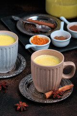 Easy Healthy Golden Milk, Turmeric Latte over dark background. Spices for ayurvedic treatment. Alternative medicine concept.