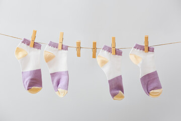 New socks hanging on rope against grey background