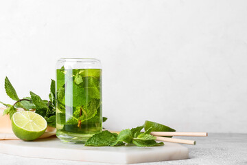 Glass of tasty mint tea with lime on white background
