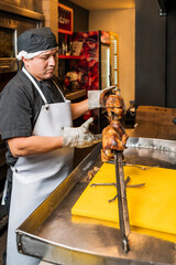 Chef removing the stake where the chickens are placed on the grill