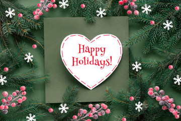 Green red Christmas background with text Happy Holidays on white paper heart shape. Natural Xmas...