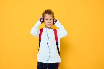 schoolboy with headphones music Red backpack yellow background