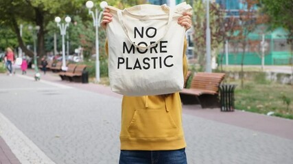 A woman shows a bag with the inscription no more plastic and holds it instead of her head