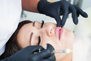 Doctor cosmetologist prepares the patient for the lip augmentation procedure with filler injection.