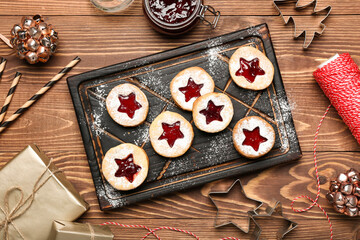 Board with tasty Linzer cookies and Christmas decor on wooden background