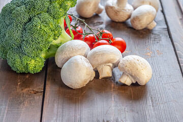vegetable background of broccoli, mushrooms and cherry tomatoes on an old wooden surface