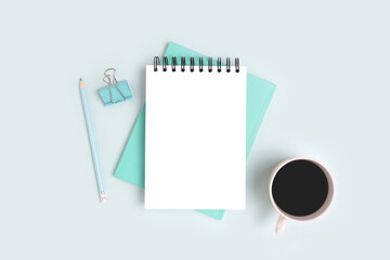 Workspace with open notepad mockup, stationery and coffee cup on a blue background. Monochrome business concept.
