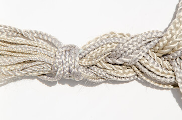 Many synthetic fiber braids with different weaves, gathered in one braid on a white background. Texture. Hairdressing material - kanekalon